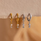 Two pairs of Dangling Pearl Diamond Huggies—one gold, one silver—feature pearls and small crystals, ideal for pearl earring lovers or anyone seeking elegant, sparkling hoop earrings.