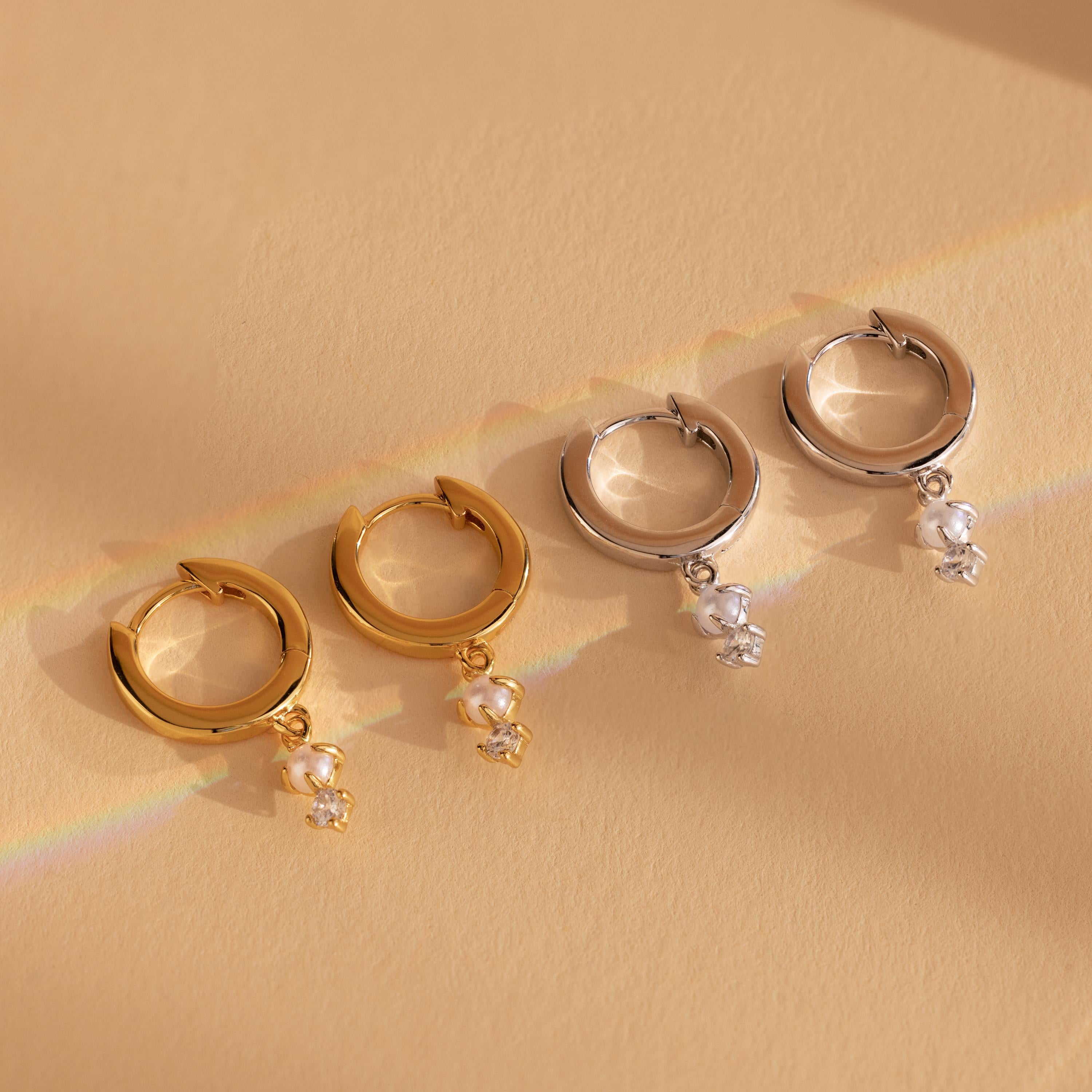 Our Dangling Pearl Diamond Huggies feature gold and silver hoops adorned with delicate pearls and sparkling crystal charms, adding a touch of timeless elegance to any look.