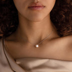 A woman showcases the Classic Pearl Pendant Necklace on a delicate chain, paired with a satin off-shoulder top for an effortlessly elegant, minimalist look.