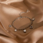 The Heart Charm Bracelet features delicate heart charms on smooth beige satin—an elegant and thoughtful gift for your girlfriend.