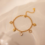 The Heart Charm Bracelet features delicate heart charms and is shown on a soft beige background—making it the perfect gift for your girlfriend.