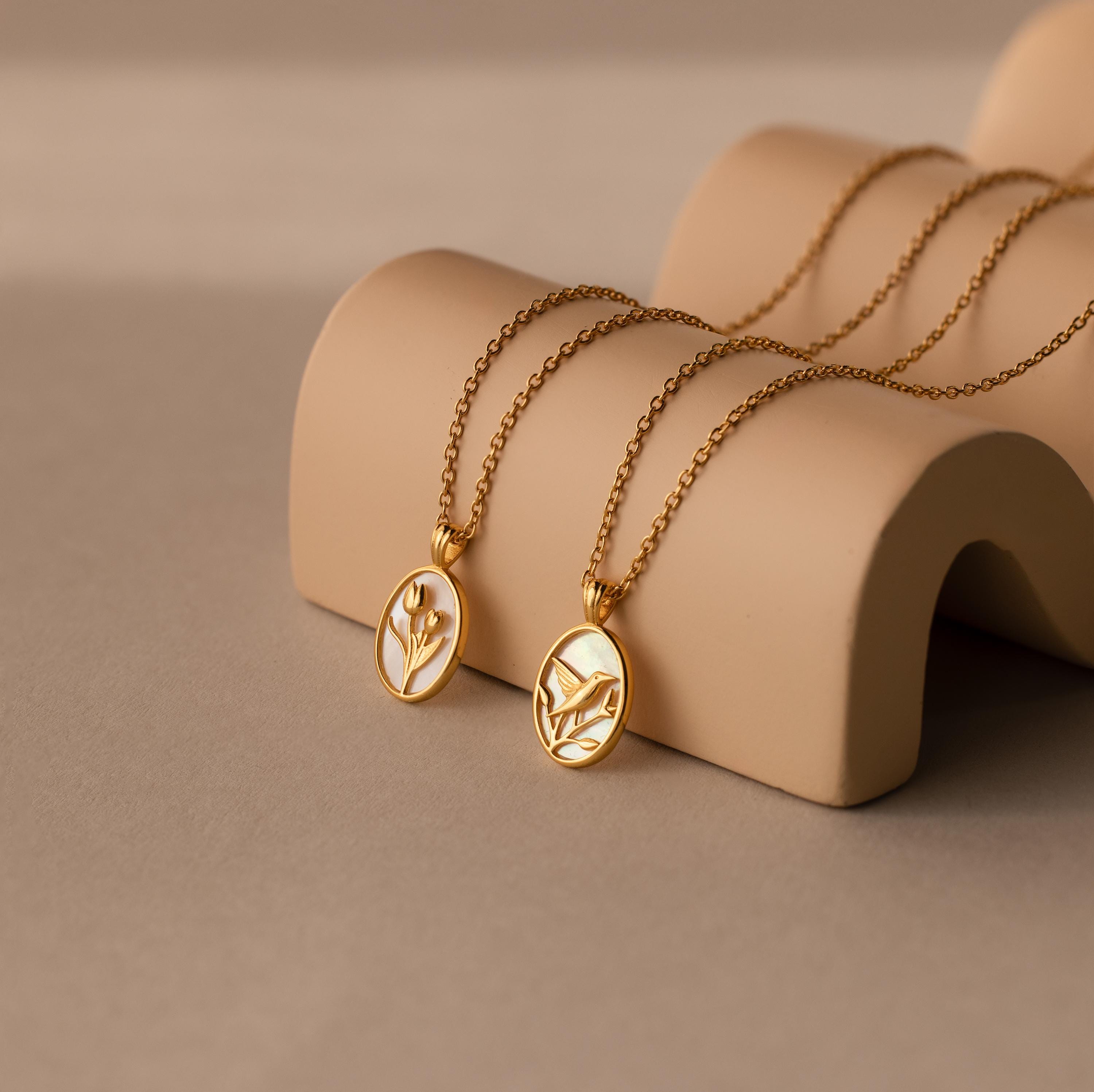 The Pearl Tulip Necklace features an elegant floral pendant, displayed on a beige curved stand—perfect for anyone who loves sophisticated Flower Jewelry.