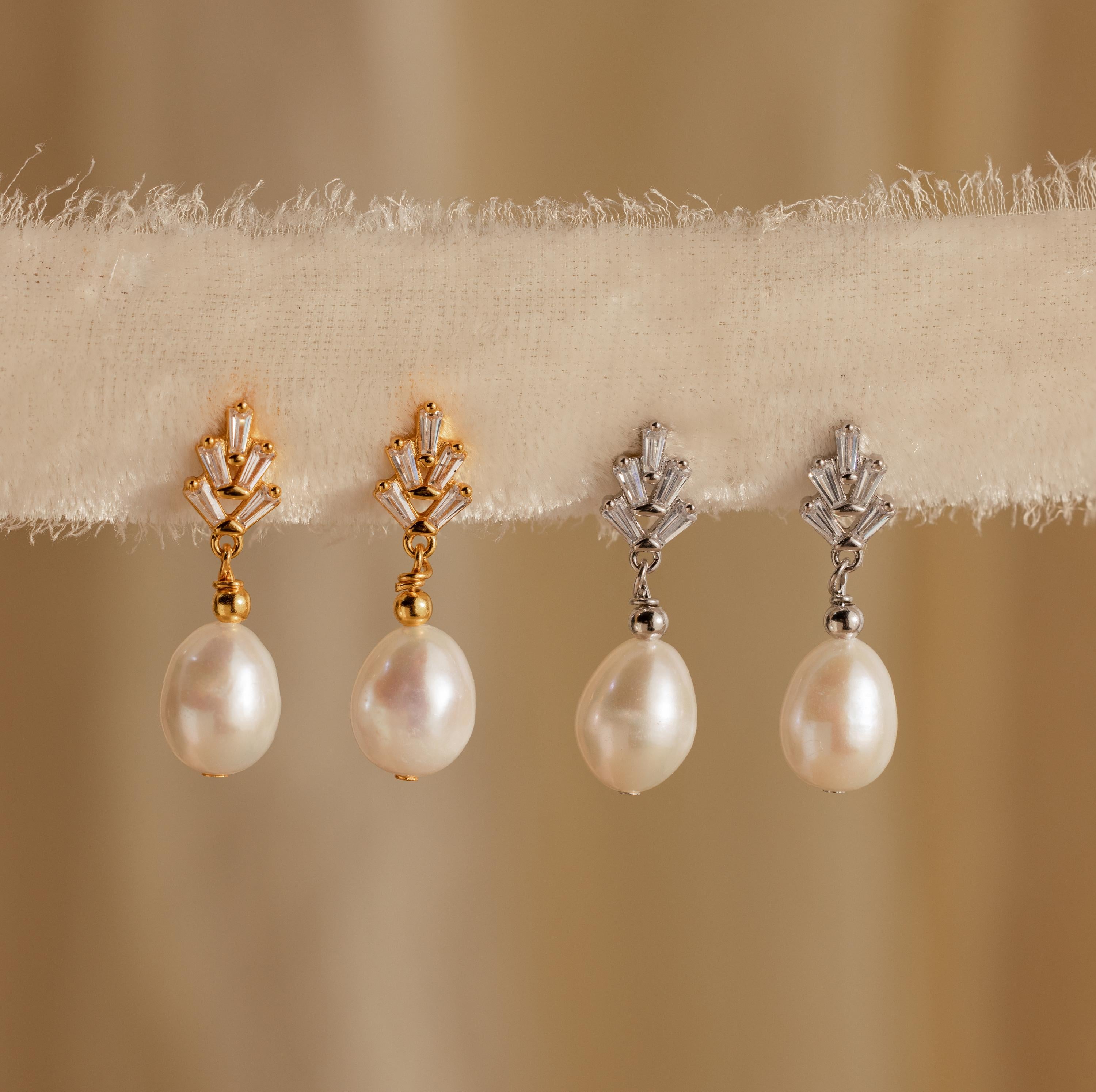 Two pairs of Pearl Diamond Drop Earrings, one accented with gold and one with silver, are displayed on a textured fabric strip—ideal for those who appreciate the elegance of Pearl Diamond Drop Earrings.
