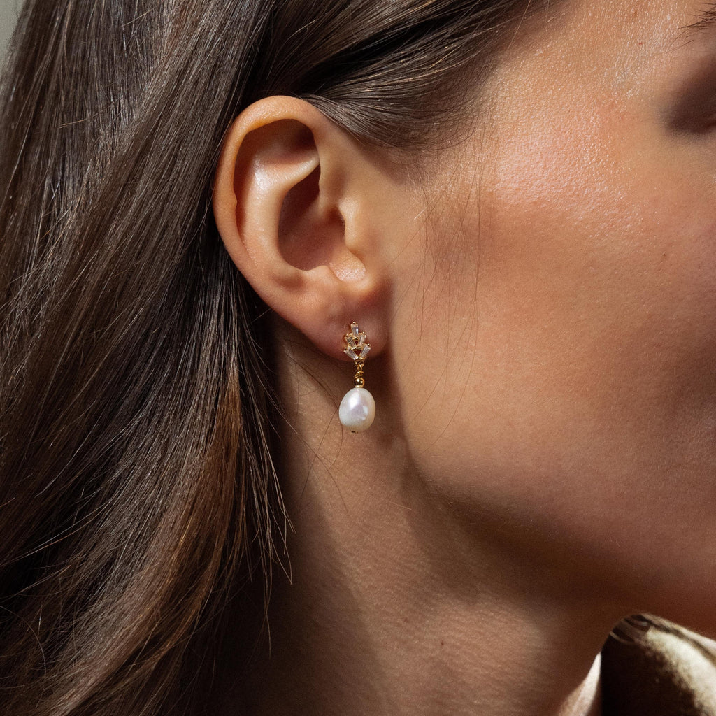 A close-up of a woman’s ear adorned with elegant Pearl Diamond Drop Earrings.