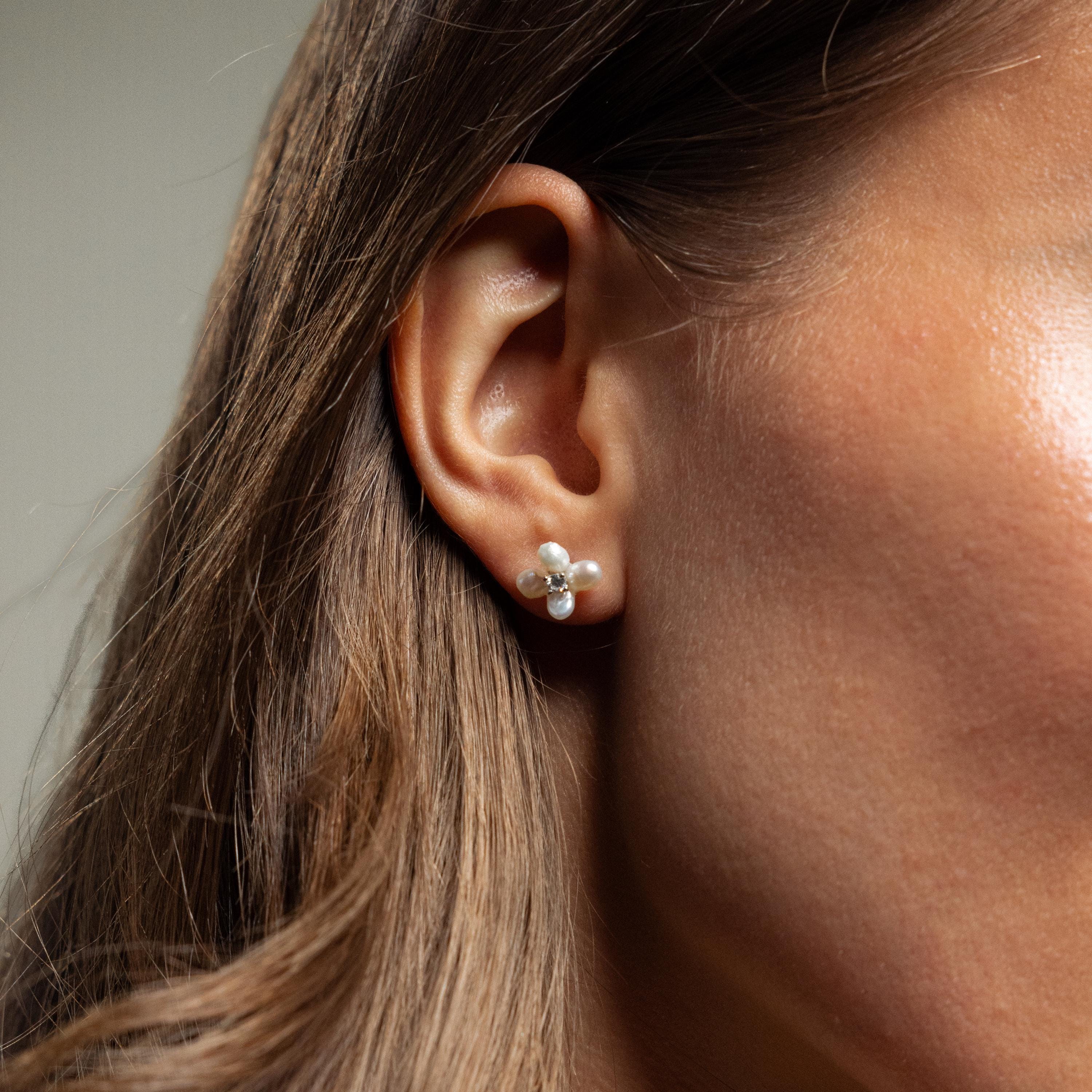 Close-up of a woman's ear wearing Pearl Flower Studs—delicate, floral-inspired earrings that bring elegant charm to any outfit.