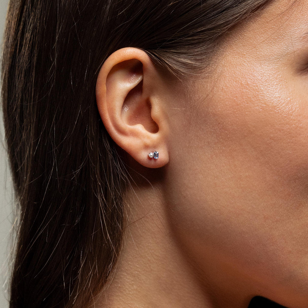 Close-up of a woman's ear wearing Pearl Aquamarine Studs—small, round silver stud earrings featuring aquamarine gemstones.