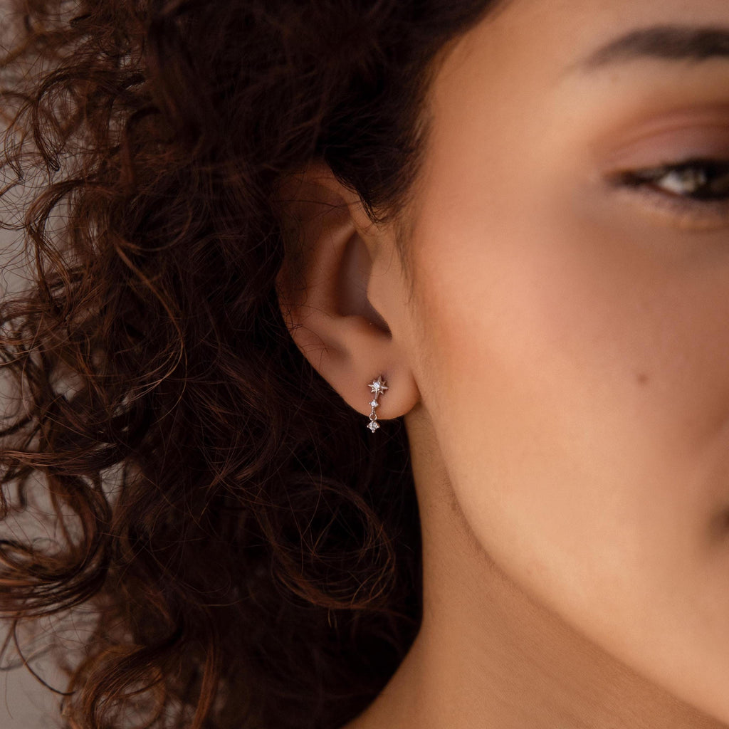 Close-up of a woman with curly hair wearing Diamond Starburst Drop Studs in Sterling Silver, adding a subtle sparkle to her look.