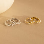 Two pairs of pearl earrings, featuring elegant Pearl Cluster Huggies in Sterling Silver, displayed on a beige surface—ideal as bridal earrings or for any special occasion.