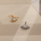 One gold and one silver Pave Evil Eye Charm laying side by side