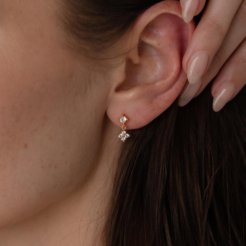 Close-up of a woman's ear wearing Ivy Flower Flat Back Studs in 18K Gold with small dangling crystals—elegant earrings perfect as a Mother's Day gift.