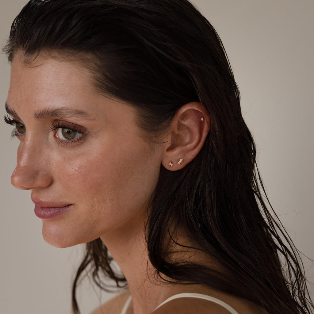 Woman with wet dark hair, wearing small gold Marquise Opal Flat Back Studs, looks to the left against a neutral background.