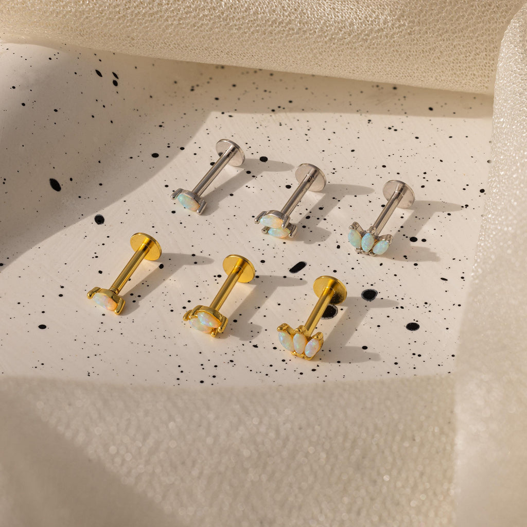 Six Marquise Opal Flat Back Studs—three silver, three gold—feature shimmering opals and are elegantly displayed on a speckled ceramic tray, making them a perfect gift for her.
