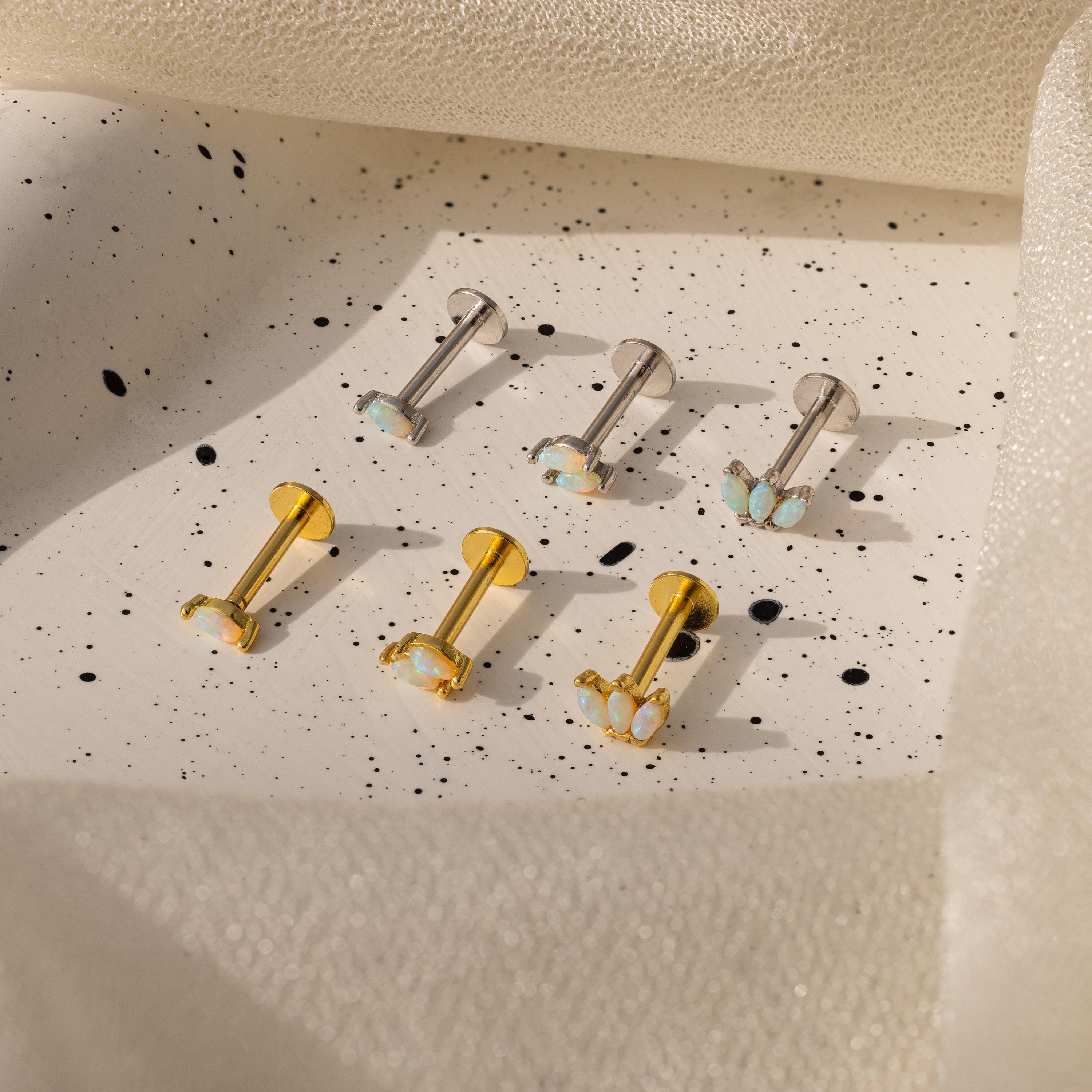 Six Marquise Opal Flat Back Studs—three silver, three gold—feature shimmering opals and are elegantly displayed on a speckled ceramic tray, making them a perfect gift for her.