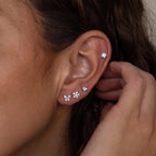 Close-up of an ear wearing the Pave Assortment Flat Back Set, featuring sparkling flat-back studs, as a hand gently touches the ear.
