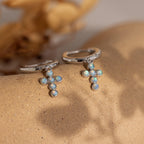 Enhance your style with the Opal Cross Huggies, adorned with dainty opal cross charms for an elegant, timeless touch.
