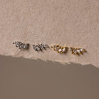 The Marquise Diamond Climbers—two pairs of leaf-shaped stud earrings in silver and gold—evoke wedding jewelry elegance, beautifully displayed on textured beige paper.