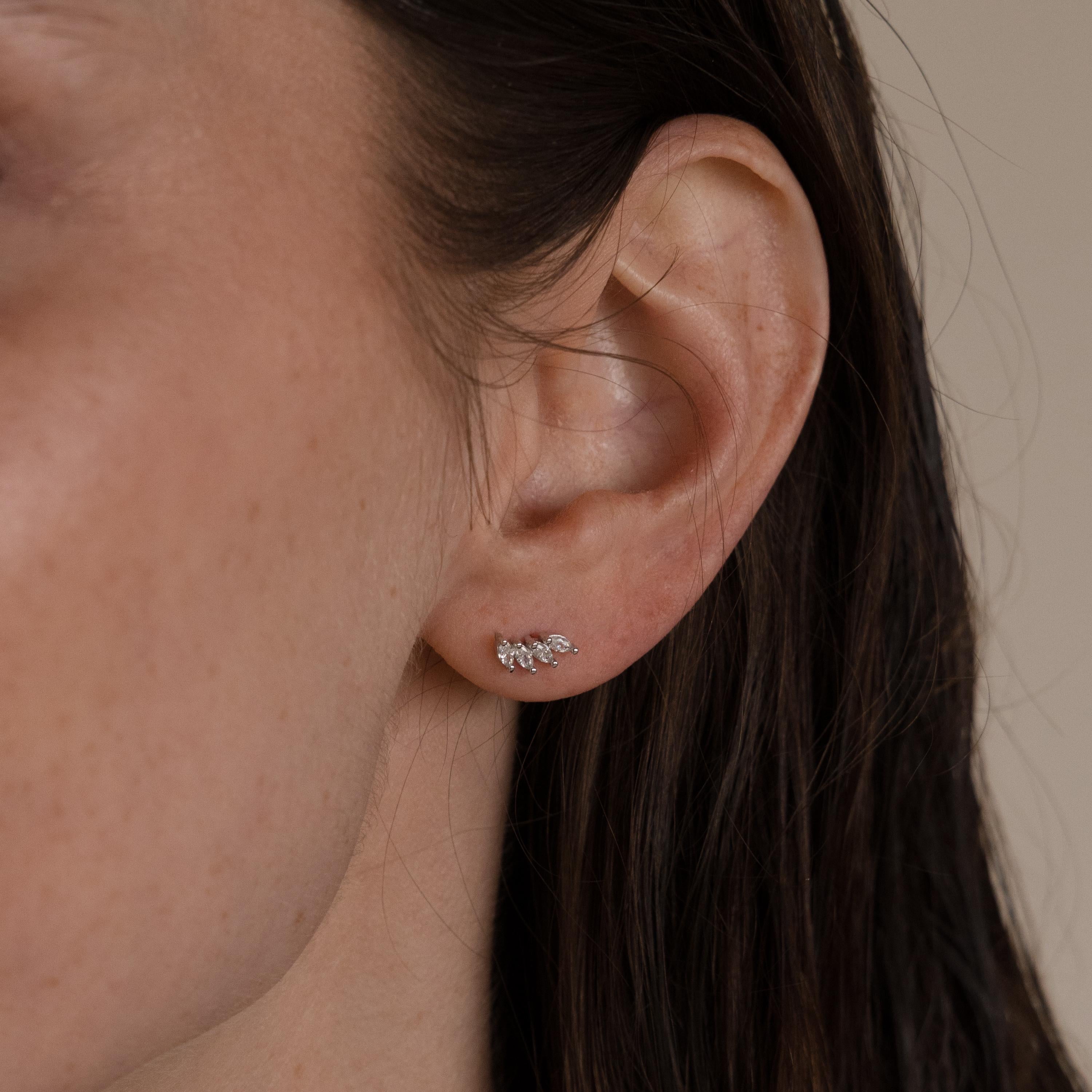 Close-up of a woman's ear adorned with Marquise Diamond Climbers, delicate silver earrings shaped like leaves—perfect for pairing with diamond studs or as refined wedding jewelry.