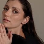 Woman with wet, dark hair wears a black top and Large Diamond Bezel Flatback Studs, gazing softly at the camera.
