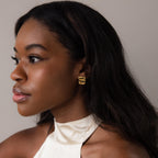 A woman gazes to the side, elegantly showcasing Bold Square Wave Studs.