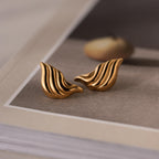 A pair of Bold Wing Studs rests elegantly on a book.