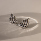 Bold Wing Studs: Silver stud earrings with a wavy, abstract design inspired by bold wing shapes, displayed on a neutral background.
