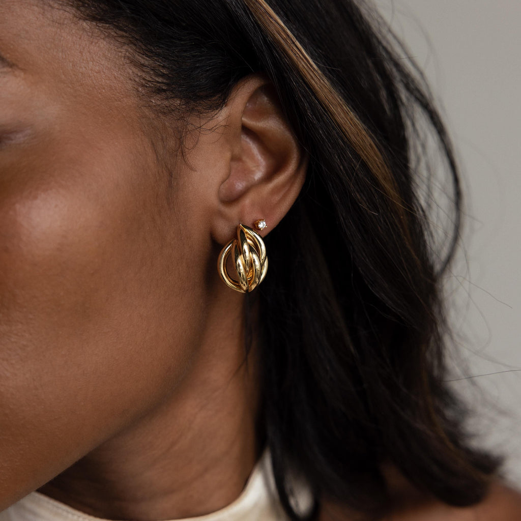 Close-up of a woman's ear adorned with Bold Multi Knot Studs, showcasing modern elegance as her dark hair frames the statement earring.