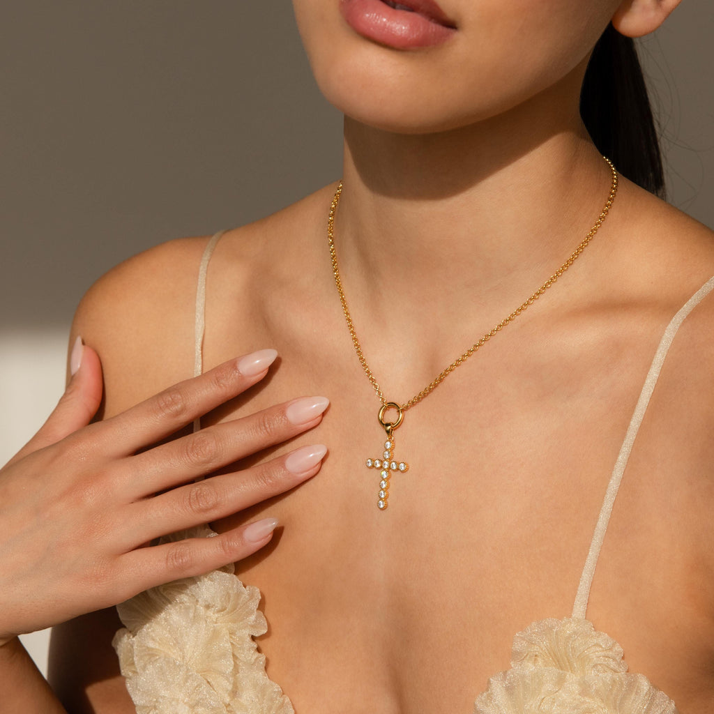 Model wears gold Rolo Necklace with a dangling gold Pave Cross Charm