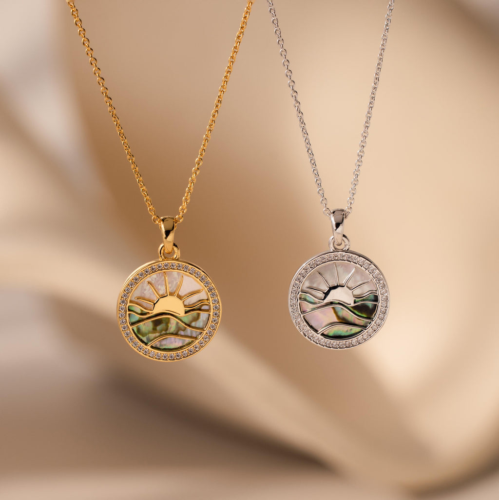 The Abalone Sunrise Pendant Necklace, available in gold and silver with a sun and mountain design, makes a stunning pair—perfect for layering with your favorite pavé diamond necklace.