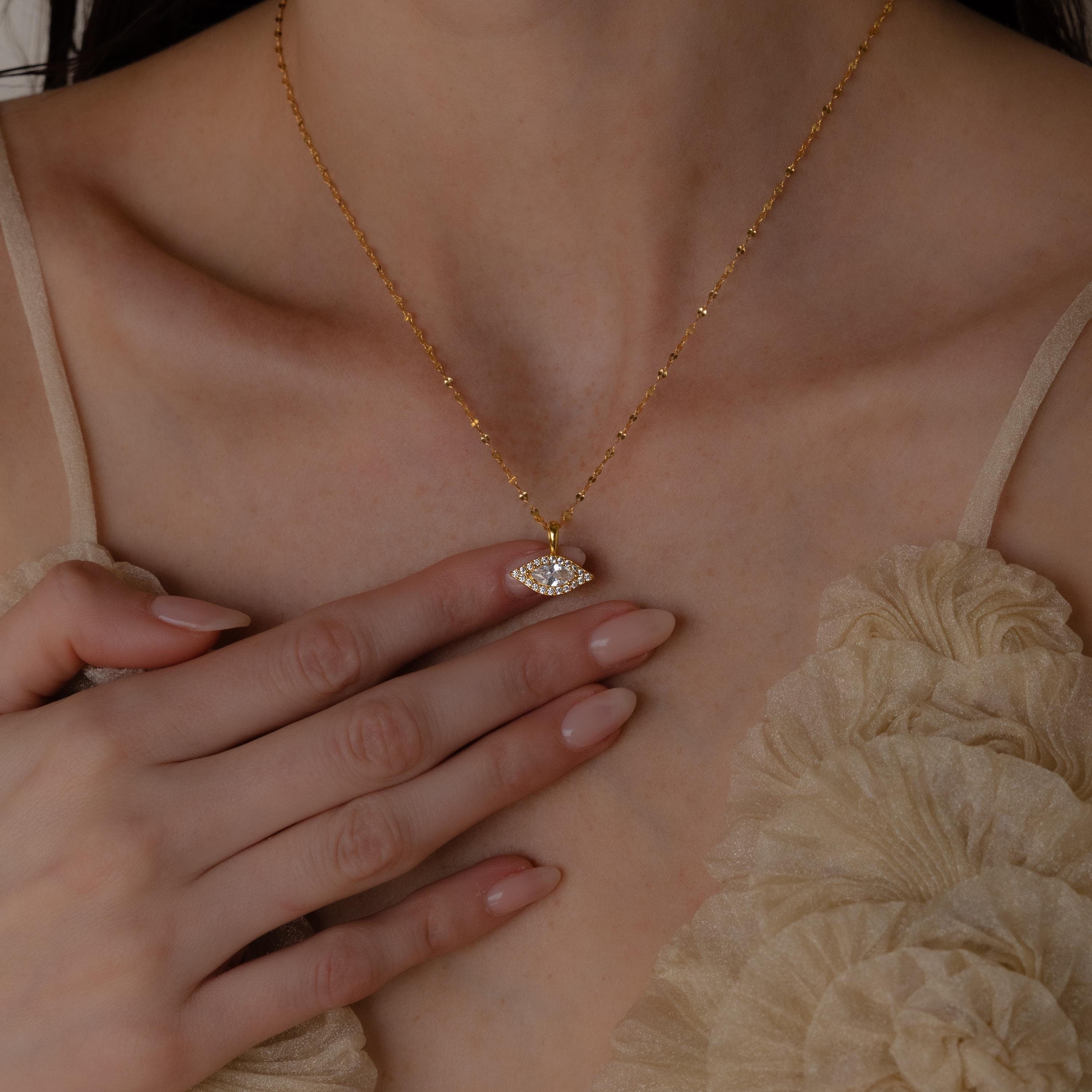 Model wears gold mirror chain with dangling Pave Evil Eye Charm