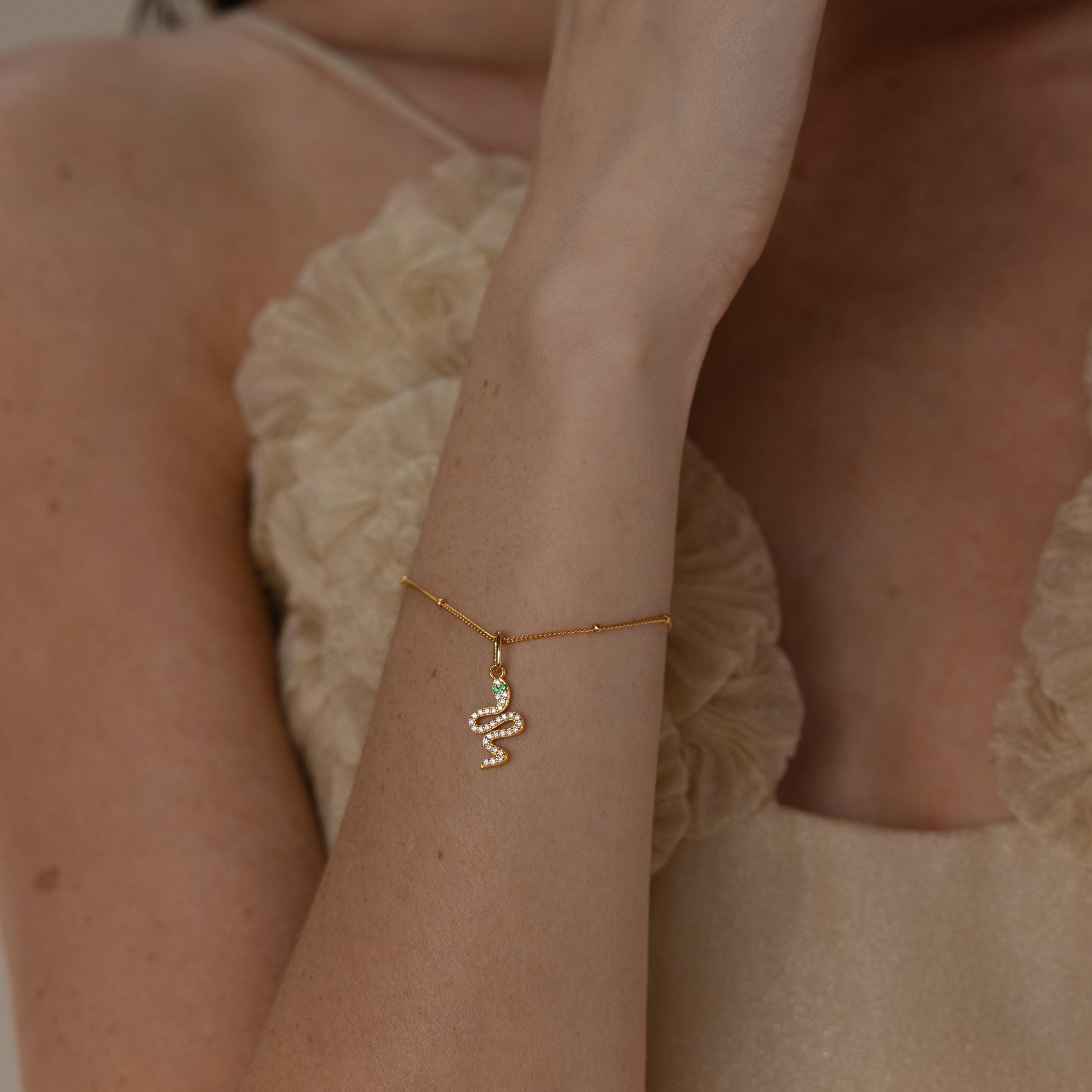 Model wears gold diamond snake charm hanging from a satellite bracelet
