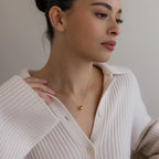 Woman in a cream ribbed sweater wears the Pave Duo Circle Necklace, its elegant jewelry design catching the light as she gazes thoughtfully to the side.