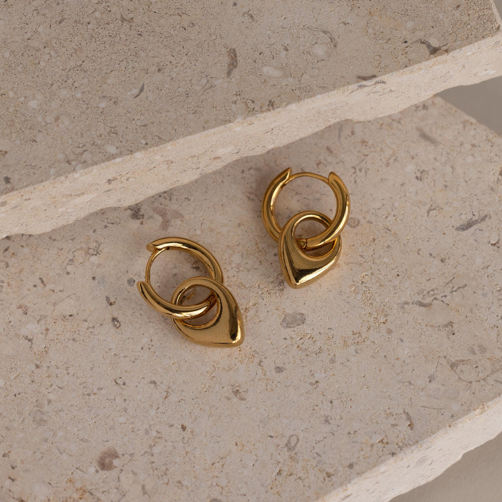 Bold Teardrop Hoops with a modern, linked design displayed on textured stone slabs—these versatile earrings elevate any look.