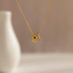 The Pave Duo Circle Necklace features two pendants—one plain, one with pavé stones—for a dainty, elegant look, shown beautifully in front of a blurred vase.