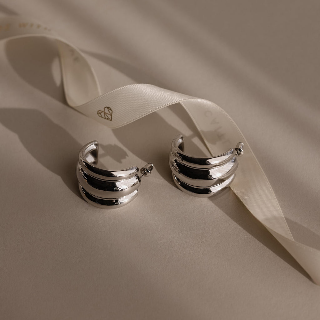 Chunky Triple Hoops: Silver statement earrings with a ribbon and chic, chunky triple hoops design.