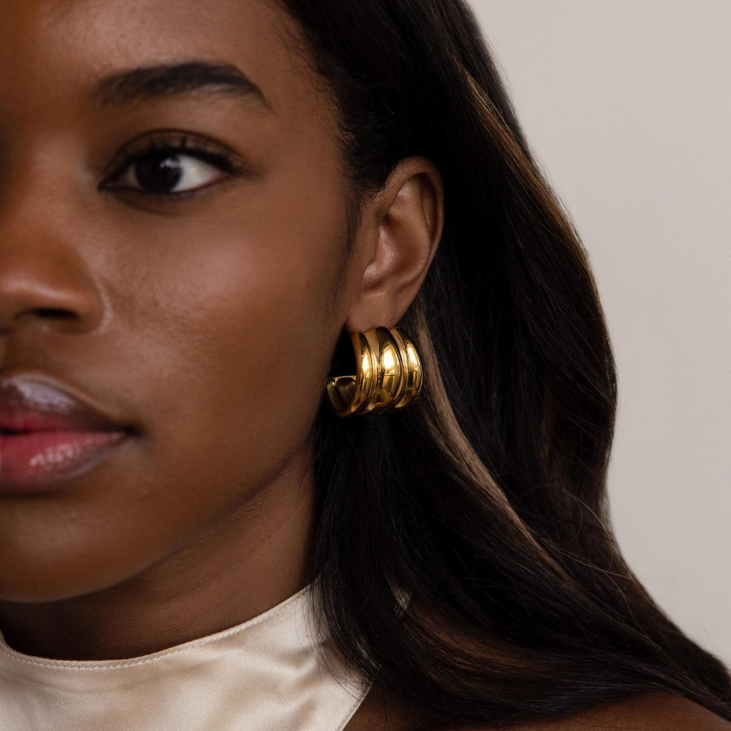 Close-up of a woman in a cream satin top and smooth dark hair, wearing Chunky Triple Hoops.