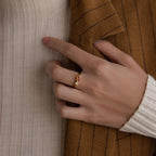 A hand adorned with the Toi et Moi Infinity Birthstone Ring featuring a red custom gemstone rests on a brown pinstripe jacket, symbolizing an everlasting token of love.
