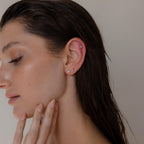 A woman with wet hair showcases multiple ear piercings adorned with the Mixed Diamond Flat Back Stud Set, gently touching her chin against a neutral background.