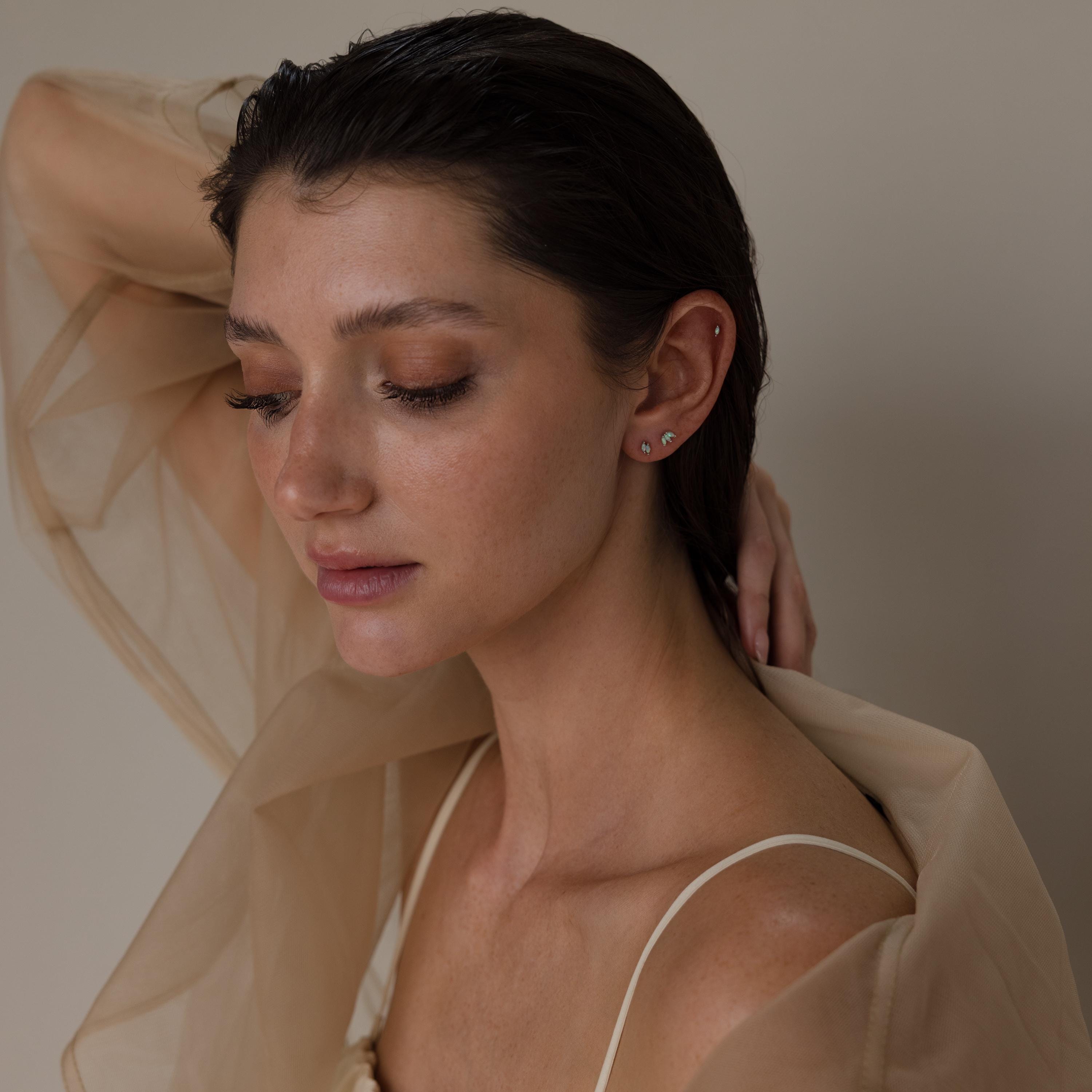 Woman with wet hair, draped in sheer beige fabric and wearing Marquise Opal Flat Back Studs, poses with eyes closed and hand behind her head—a stunning look and a perfect gift.