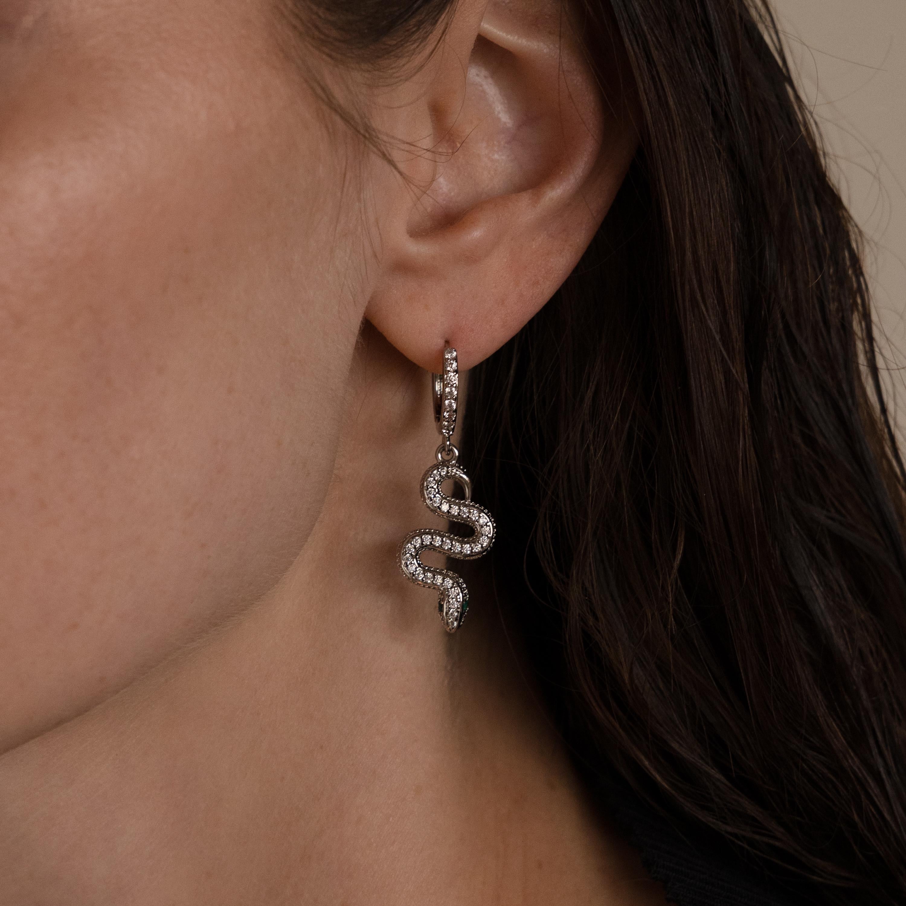 Close-up of a woman's ear wearing Pave Snake Charm Hoops, snake-shaped earrings that shimmer with clear stones.