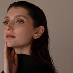 A woman with wet, dark hair in a black top touches her neck, showcasing the elegant Emerald Flat Back Earring Set.
