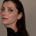 Woman with wet dark hair, natural makeup, and a black top gazes at the camera against a plain background, her look subtly elevated by Small Diamond Bezel Flatback Studs.