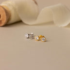 A pair of Large Diamond Bezel Flatback Studs is displayed on a beige surface with a soft fabric background.