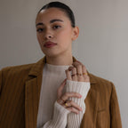 A woman in a brown pinstripe blazer and cream sweater showcases the Toi et Moi Triangle Birthstone Ring on her hand against a neutral background.
