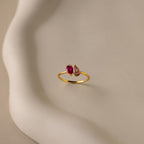 Toi et Moi Pear Birthstone Ring featuring a red and a clear gemstone, displayed on a white, curved ceramic surface—an elegant, romantic gift choice.