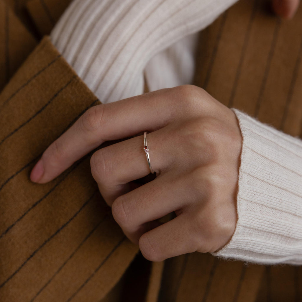 A hand wearing the Mini Toi et Moi Birthstone Ring, styled with a white sweater and a brown pinstripe coat.