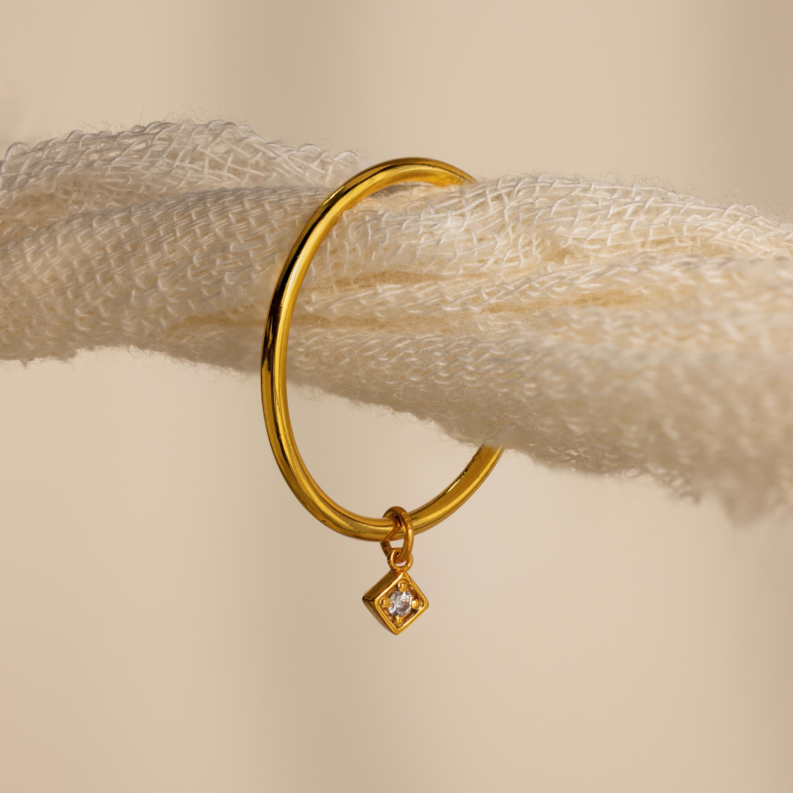 Gold hoop earring with a small diamond-shaped charm, hanging on a textured cream rope—perfect for pairing with your favorite Dainty Birthstone Drop Ring or other personalized jewelry.