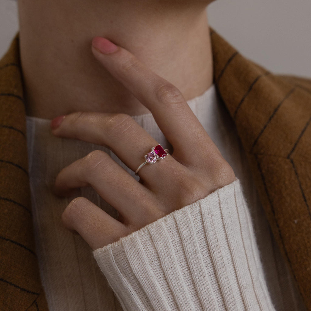 A hand wearing the Toi et Moi Emerald Birthstone Ring rests near the chin, paired with a brown-striped jacket.