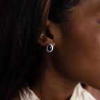 Close-up of a person wearing Vintage Oval Black Studs—retro silver statement earrings featuring a bold black center.