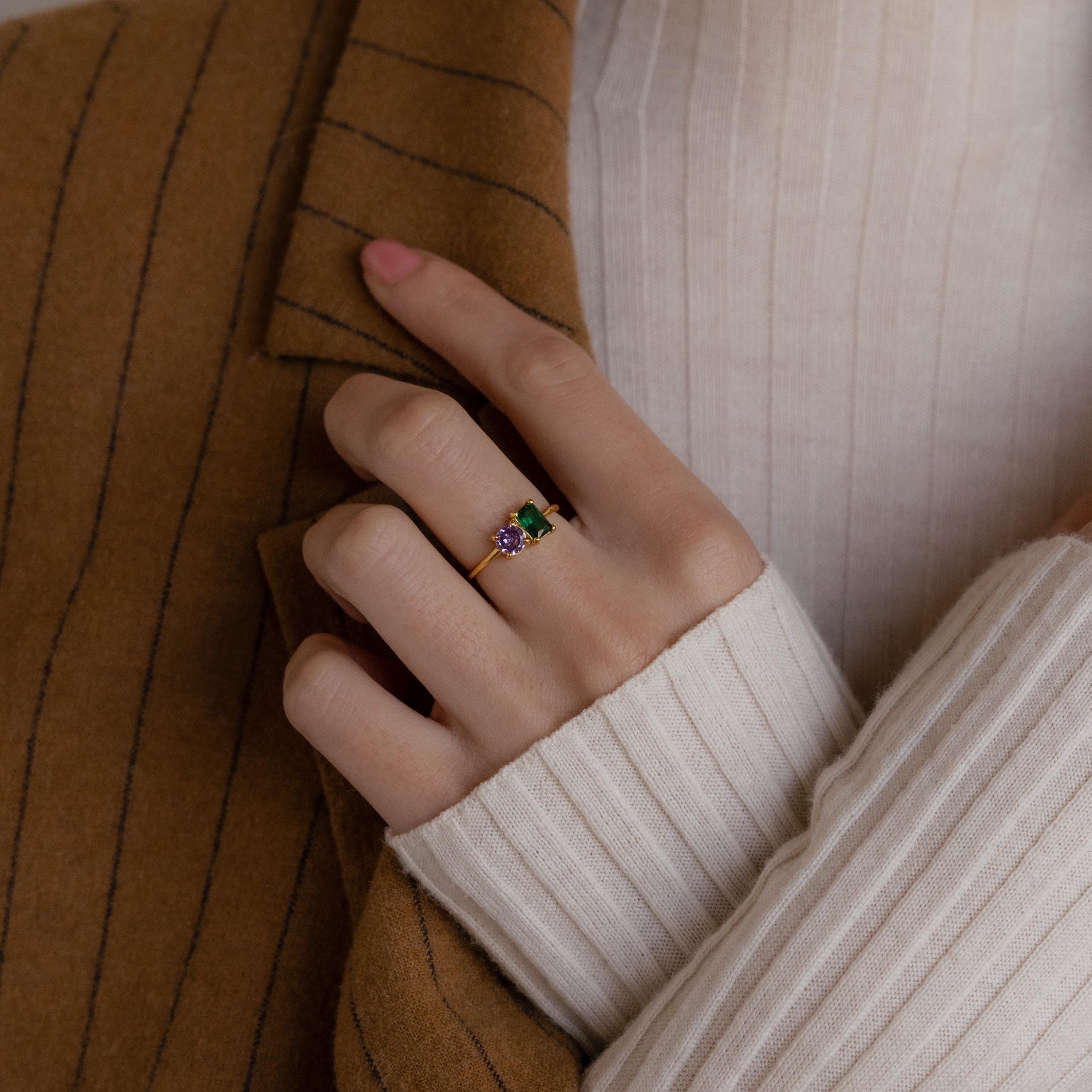Hand wearing the Toi et Moi Emerald Birthstone Ring, styled with a brown pinstripe blazer and a cream ribbed sweater.