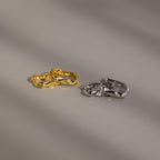 The Hammered Rectangle Hoops, featuring gold and silver textured geometric designs, are displayed side by side on a smooth, neutral surface.